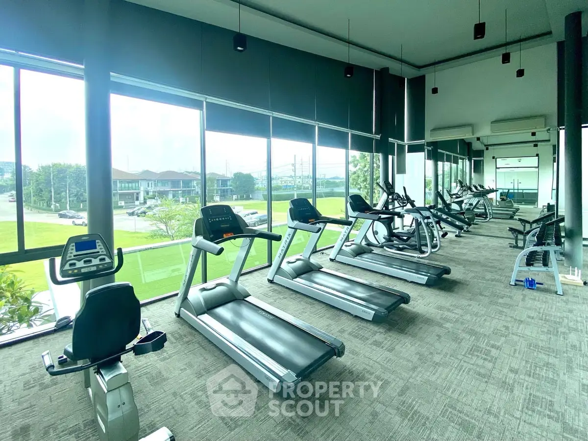 Spacious gym with modern equipment and large windows offering scenic views.