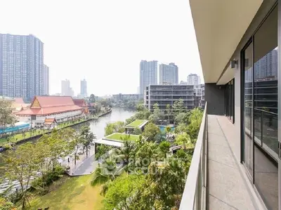 Stunning balcony view overlooking river and cityscape with lush greenery and modern buildings.