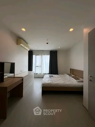 Spacious bedroom with modern furnishings and large window for natural light.