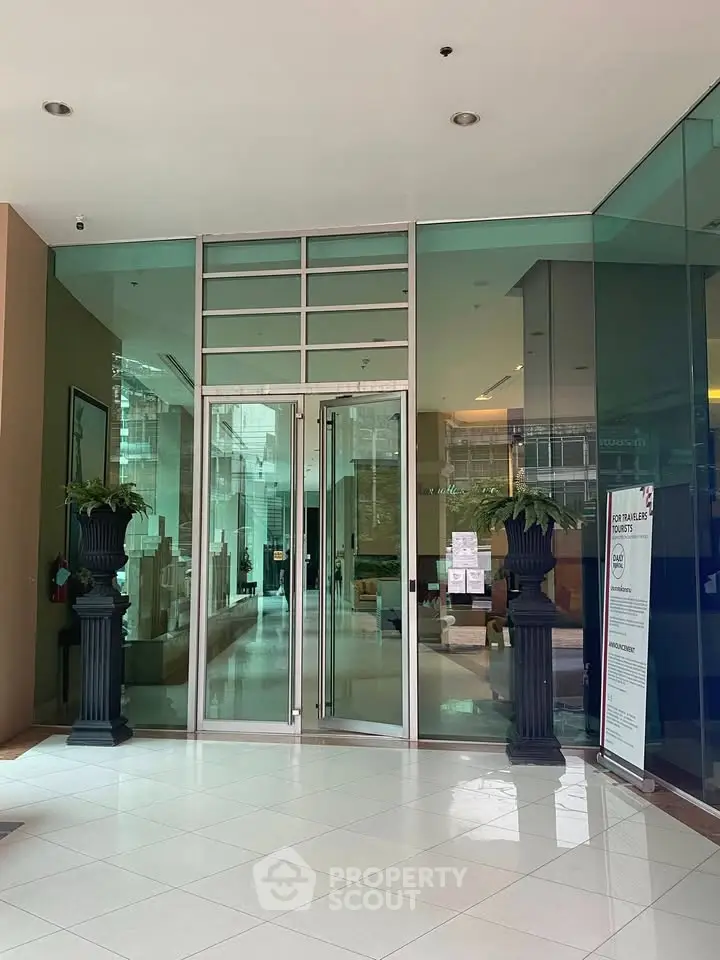 Elegant building entrance with glass doors and decorative planters.