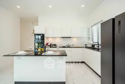 Modern kitchen with sleek black and white design, featuring island and high-end appliances.