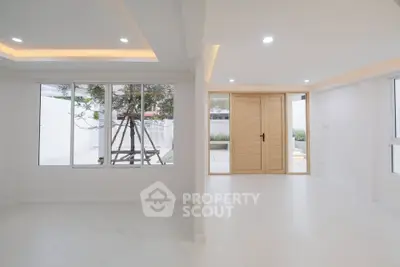 Spacious modern interior with large windows and wooden doors, perfect for natural light lovers.