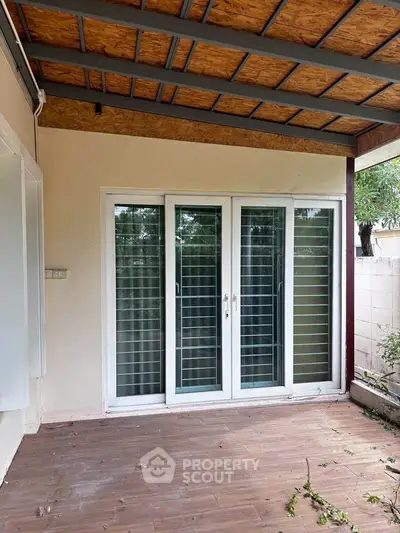 Charming patio with sliding glass doors and wooden ceiling, perfect for outdoor relaxation.