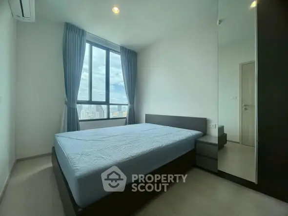 Modern bedroom with large window and city view, featuring sleek furniture and minimalist design.