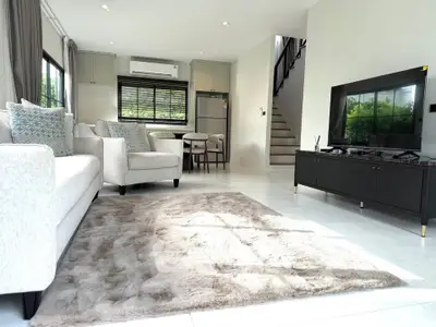 Spacious modern living room with plush carpet and stylish furniture, featuring a sleek TV unit and large windows.