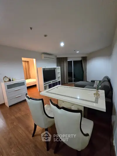 Modern living room with elegant dining area and cozy seating, featuring sleek furniture and warm lighting.