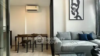 Modern living room with stylish decor and dining area, featuring sleek furniture and contemporary art.