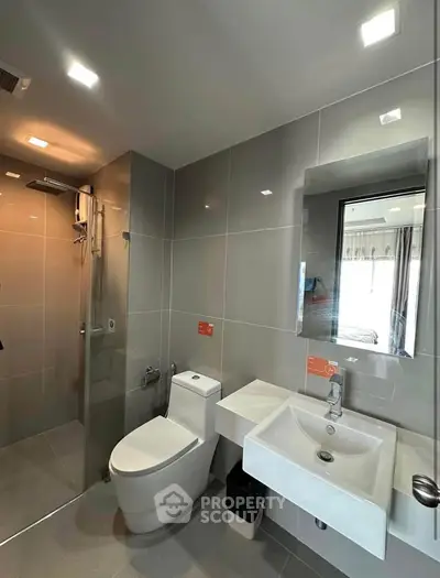 Modern bathroom with sleek fixtures and glass shower enclosure in contemporary apartment.