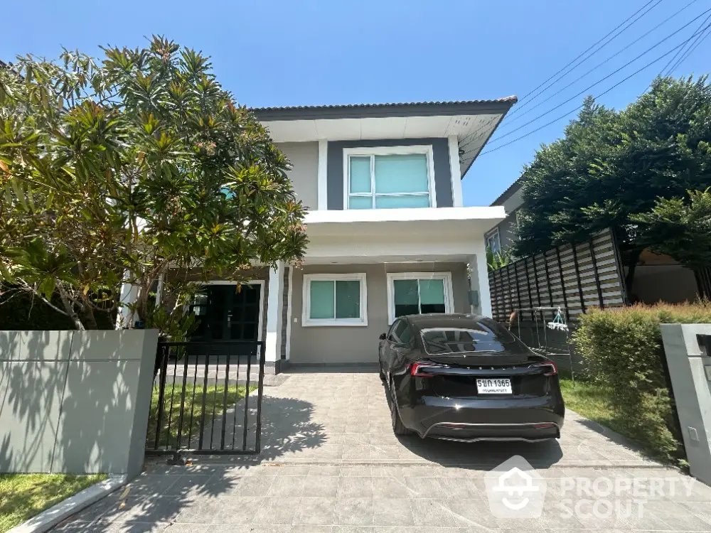 Charming two-story home with lush landscaping and modern design, featuring a spacious driveway and a welcoming entrance.