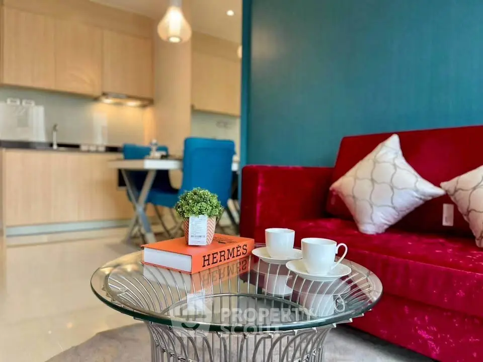 Stylish living room with vibrant red sofa and modern glass coffee table in open-plan layout.
