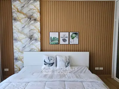 Modern bedroom with stylish decor and cozy bedding, featuring nature-themed artwork and elegant wall design.