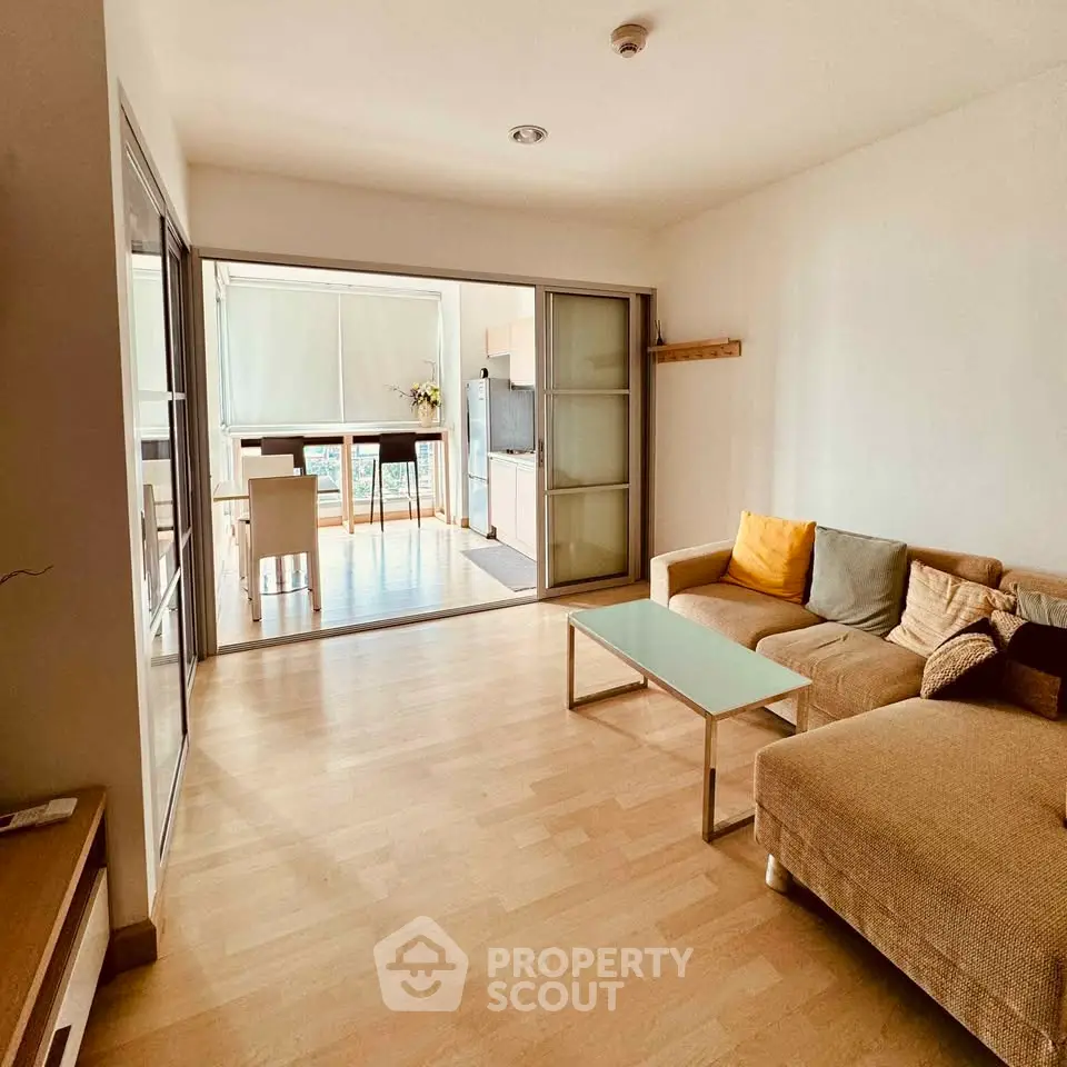 Spacious living room with modern decor and sliding glass doors leading to a bright dining area.