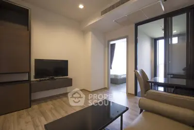Modern living room with sleek furniture and open layout leading to bedroom.
