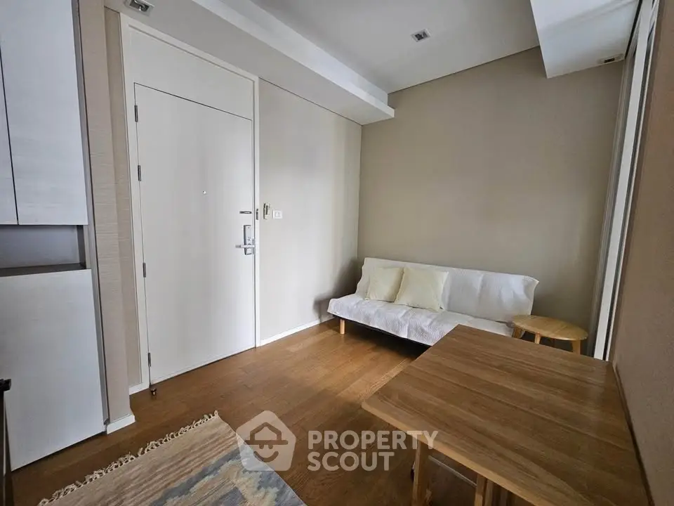 Modern minimalist living room with wooden flooring and cozy seating area.