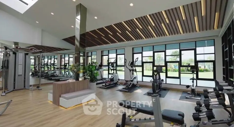 Spacious modern gym with state-of-the-art equipment and large windows offering natural light.