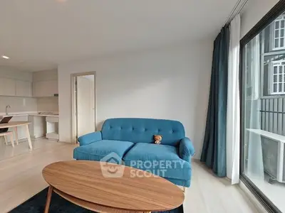 Modern living room with blue sofa and wooden coffee table, open kitchen layout.