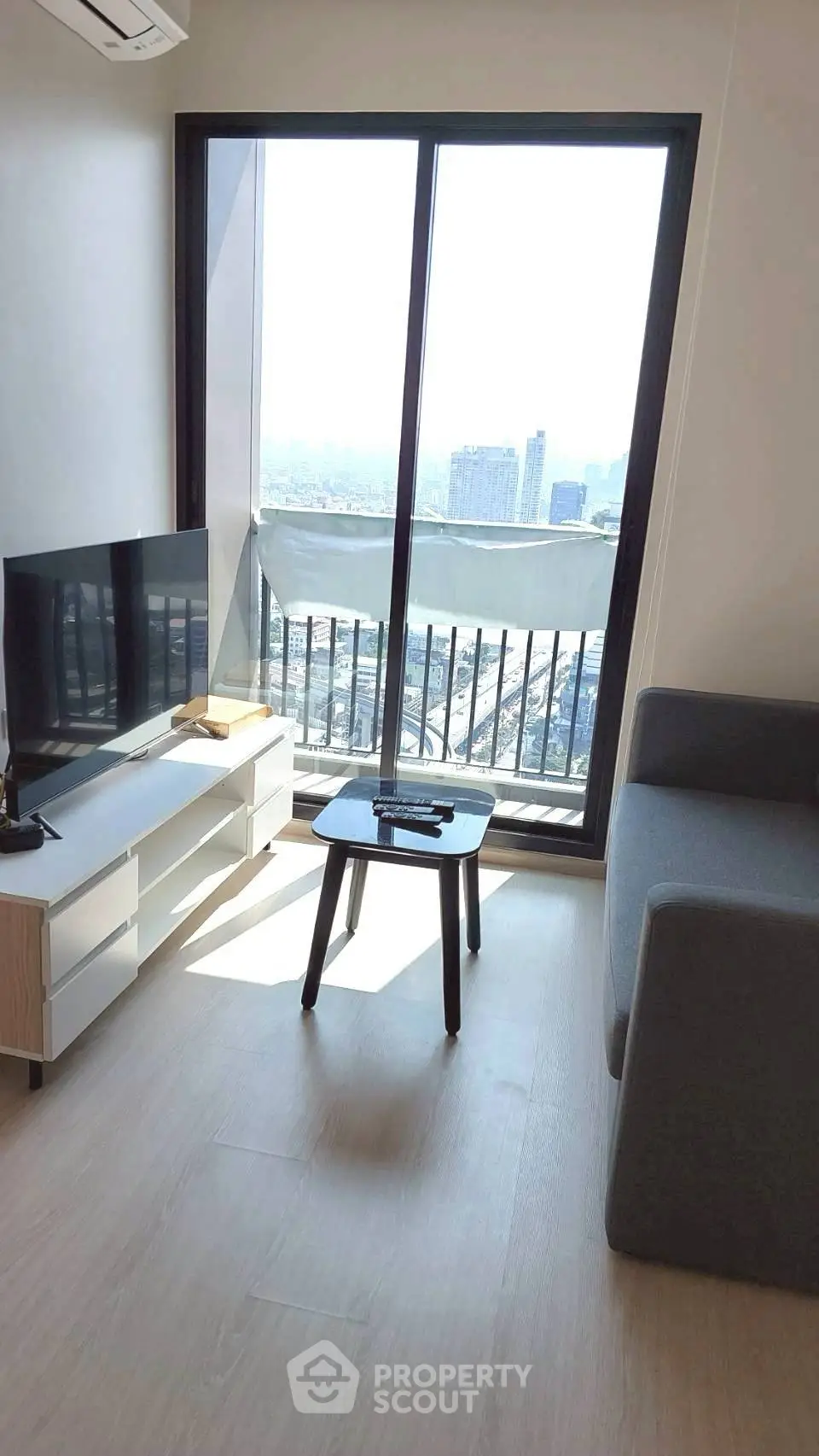 Modern living room with city view, sleek furniture, and natural light.