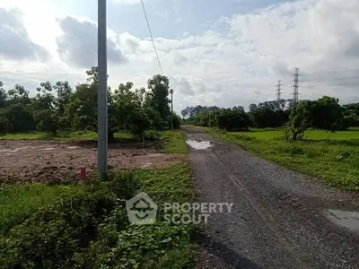 Scenic rural land with gravel road and lush greenery, ideal for development or agriculture.