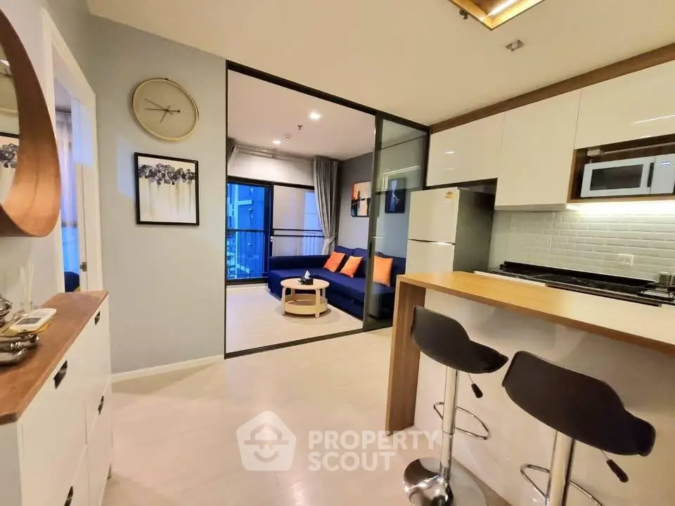 Modern open-plan kitchen and living room with stylish decor and bar seating.