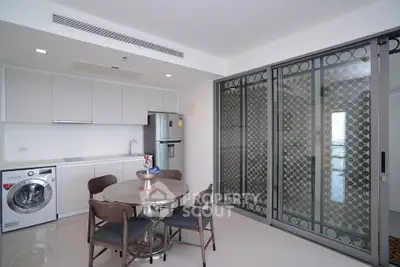Modern kitchen with dining area, washing machine, and sliding glass doors.