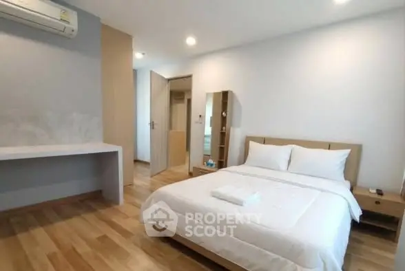 Modern bedroom with wooden flooring and air conditioning in a stylish apartment.