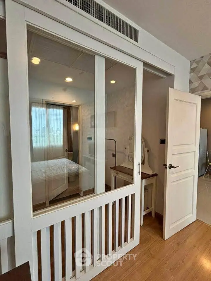 Modern bedroom with glass partition and wooden flooring in a stylish apartment.
