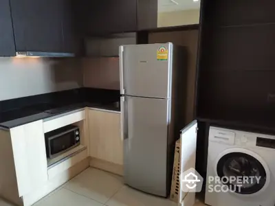 Modern kitchen with sleek appliances including fridge, microwave, and washing machine.