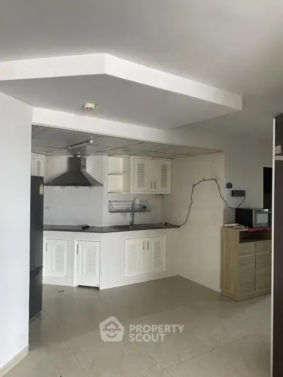 Modern kitchen with sleek white cabinets and stainless steel appliances in a cozy apartment.