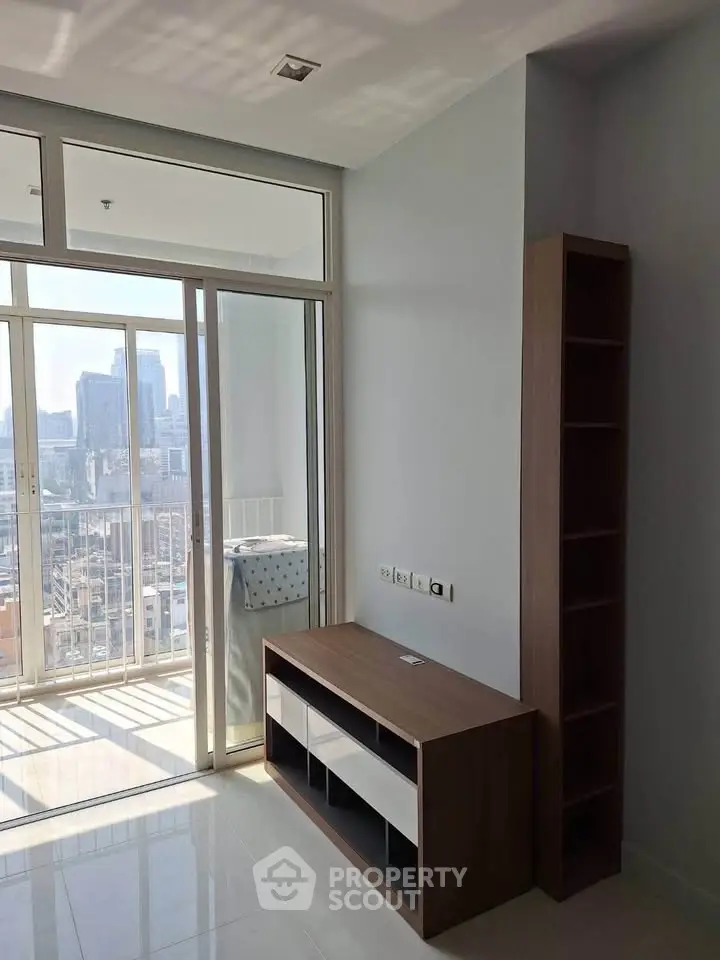 Modern apartment interior with balcony and city view, featuring sleek furniture and ample natural light.