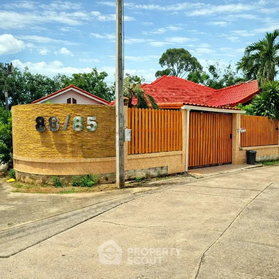 Charming villa with red roof and wooden fence in tropical setting, perfect for serene living.