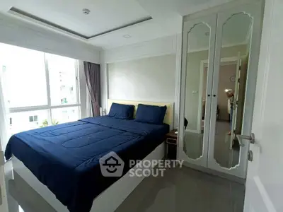 Modern bedroom with large window and mirrored wardrobe in a stylish apartment.