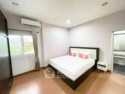Spacious bedroom with modern decor and large window offering natural light.