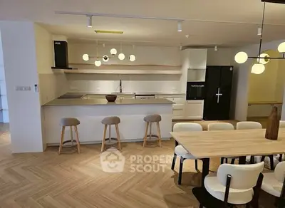 Modern open-layout kitchen with dining area, featuring sleek appliances and stylish lighting.