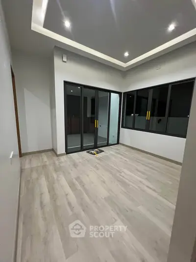Spacious modern room with large sliding glass doors and elegant ceiling lights.