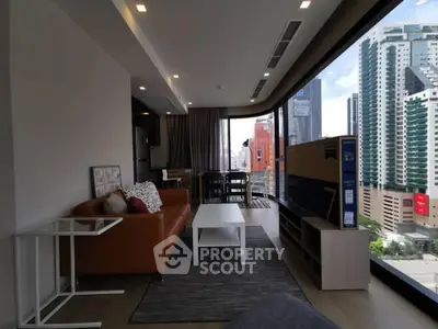 Modern living room with city view, featuring sleek furniture and floor-to-ceiling windows.