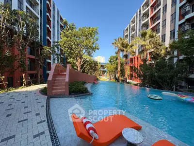 Luxurious pool area in modern residential complex with lush greenery and stylish loungers.