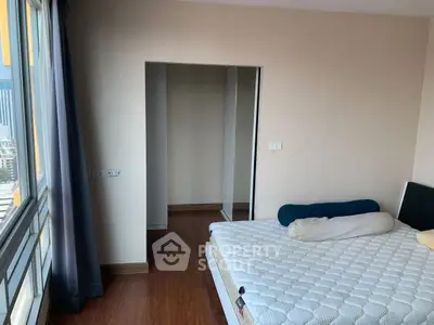 Spacious bedroom with large window and hardwood floors in modern apartment