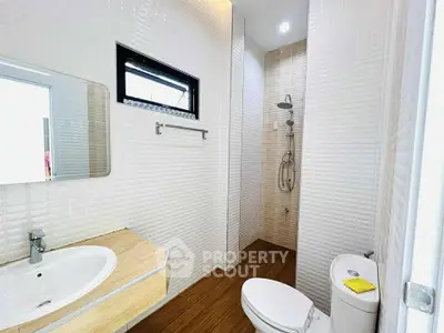 Modern bathroom with sleek fixtures and wooden flooring, featuring a spacious shower area.