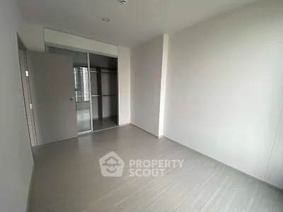 Spacious empty bedroom with sleek flooring and built-in closet in modern apartment.