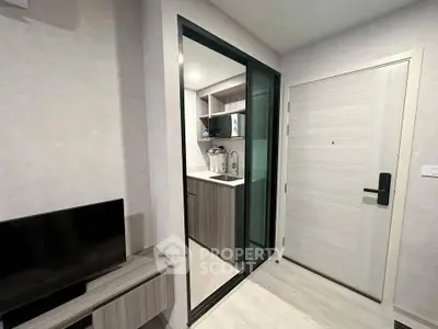 Modern compact kitchen with sliding glass door and sleek cabinetry in a stylish apartment.