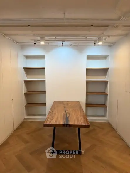 Modern study room with elegant wooden table and built-in shelves, perfect for a home office setup.