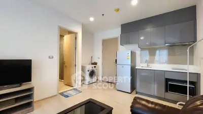 Modern apartment interior with sleek kitchen and cozy living area, featuring washing machine and fridge.