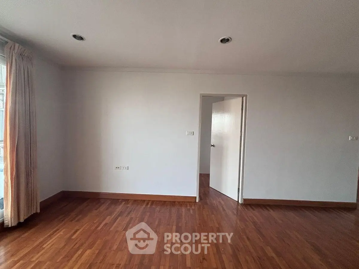 Spacious empty room with wooden flooring and natural light