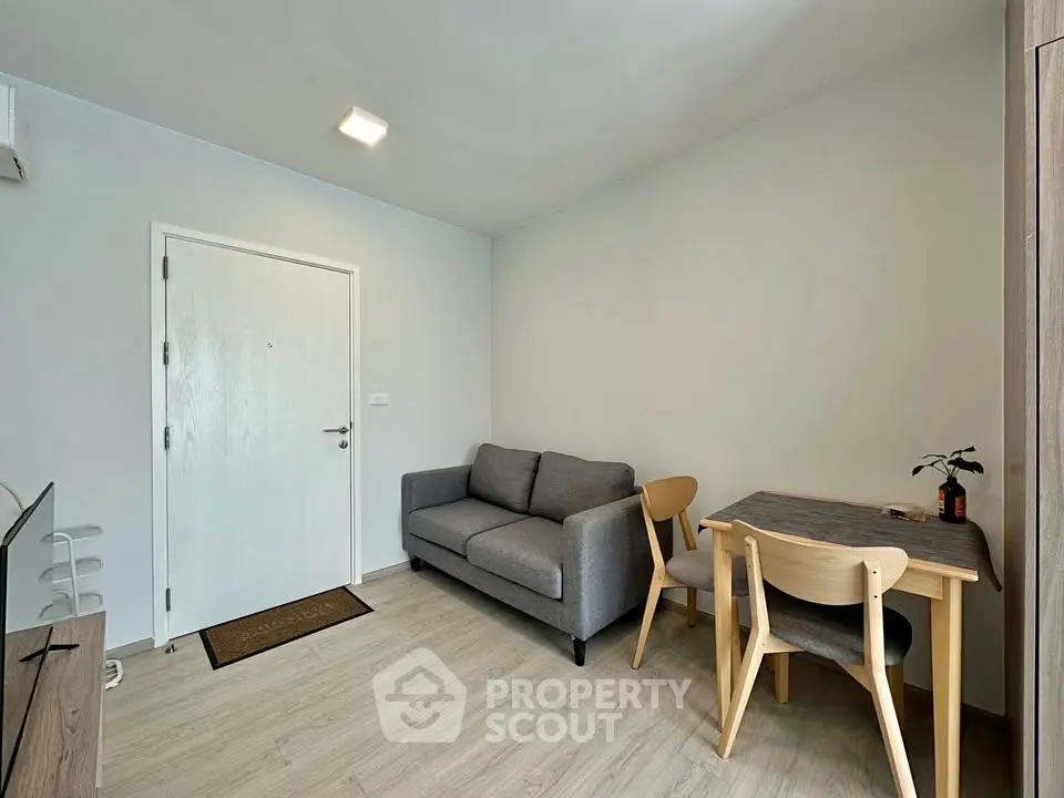 Modern living room with cozy gray sofa and wooden dining set, perfect for small apartments.