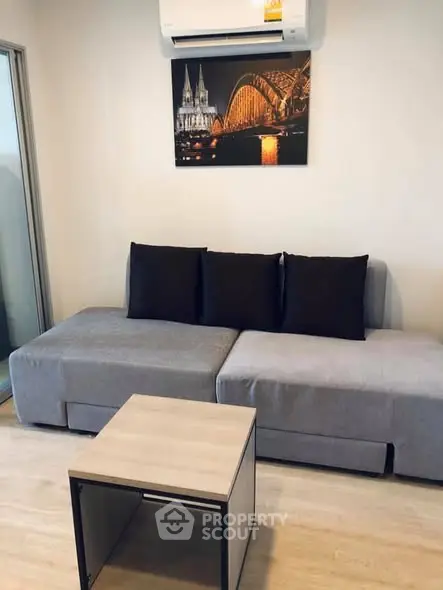 Modern living room with stylish gray sofa and wall art, featuring air conditioning for comfort.