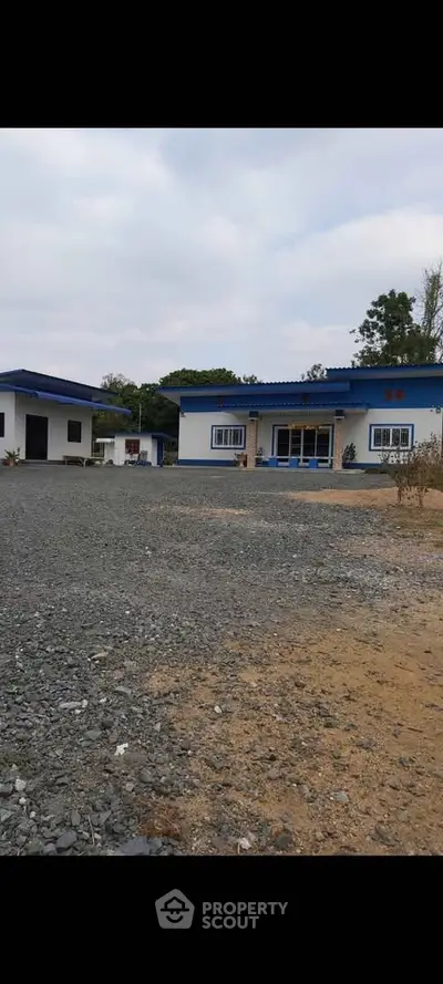 Charming countryside property with spacious yard and modern blue-roofed buildings, ideal for serene living.