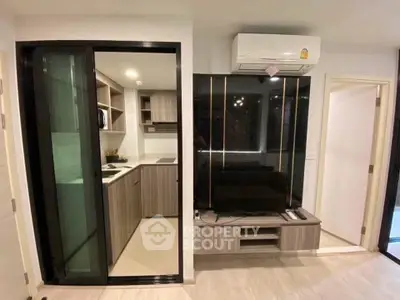 Modern apartment interior with sleek kitchen and stylish living area featuring built-in TV unit.