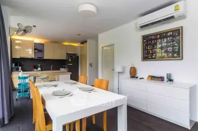 Modern dining area with sleek kitchen and stylish decor in open layout apartment.
