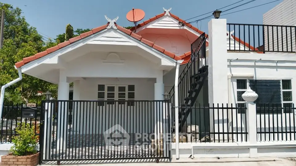 Charming single-story house with red roof and gated entrance, perfect for cozy living.