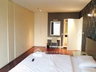 Spacious bedroom with modern decor and ample natural light, featuring a stylish accent wall and cozy furnishings.